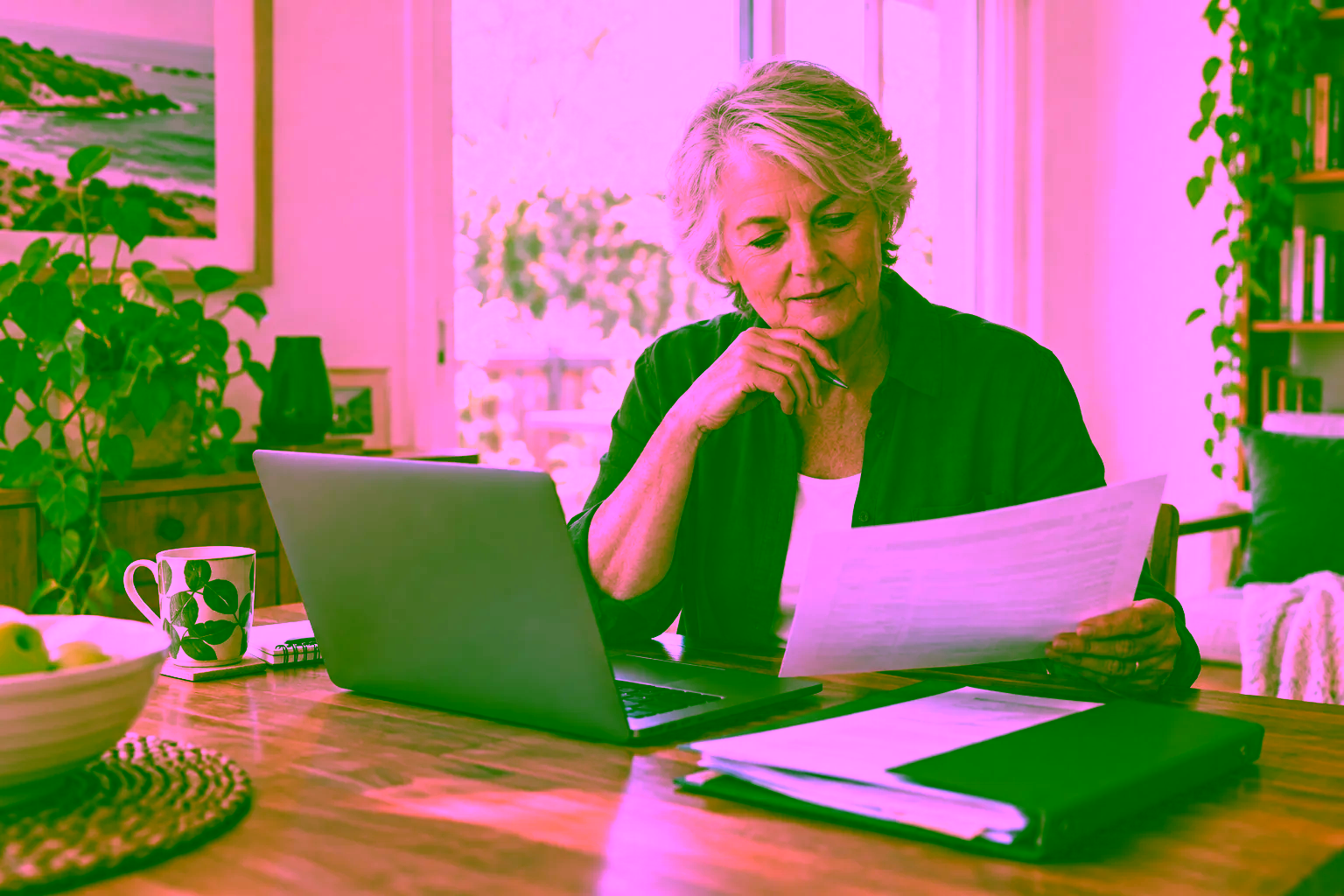 A woman reviewing financial paperwork beside her laptop