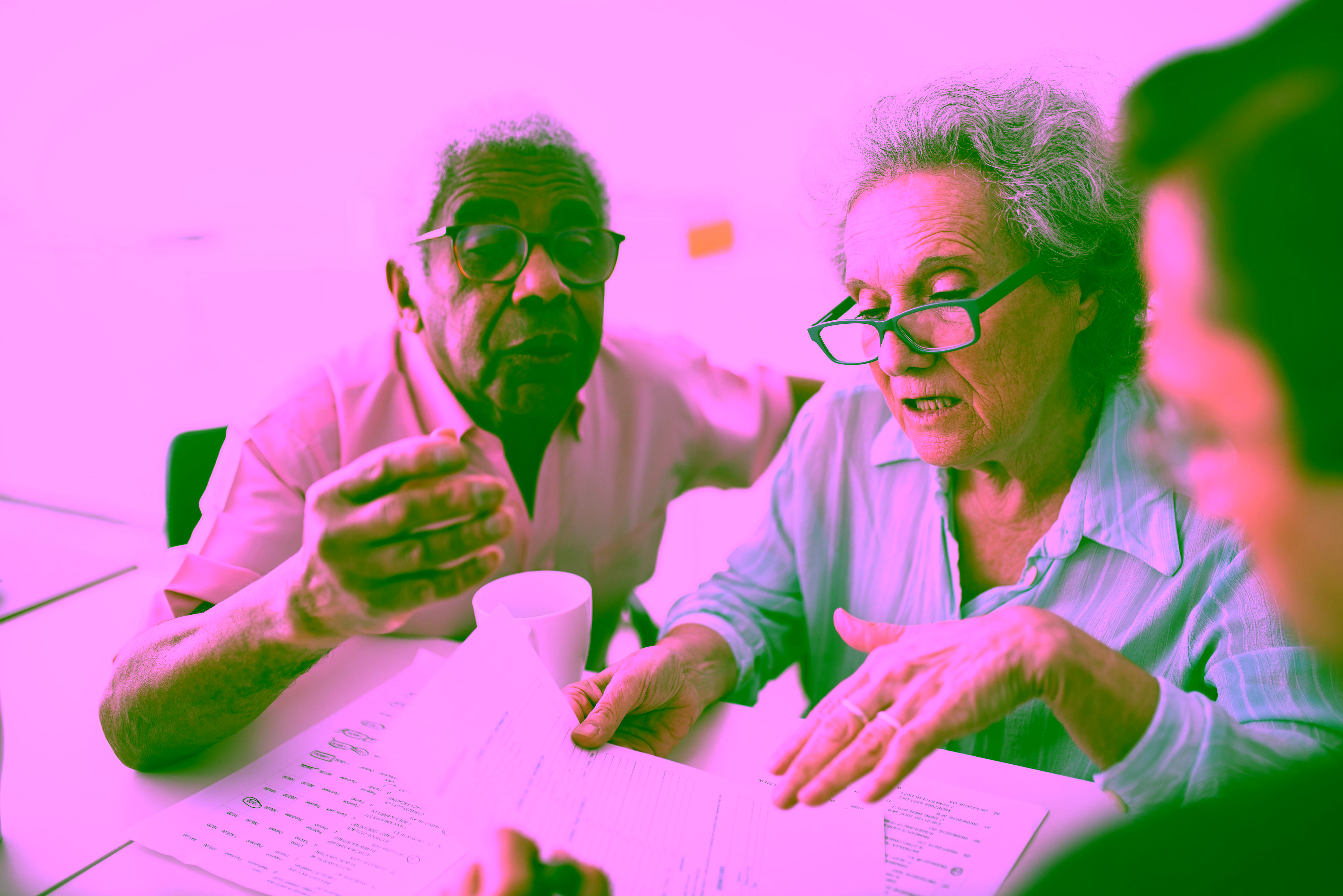 An older couple reviewing documents together with another person at a table
