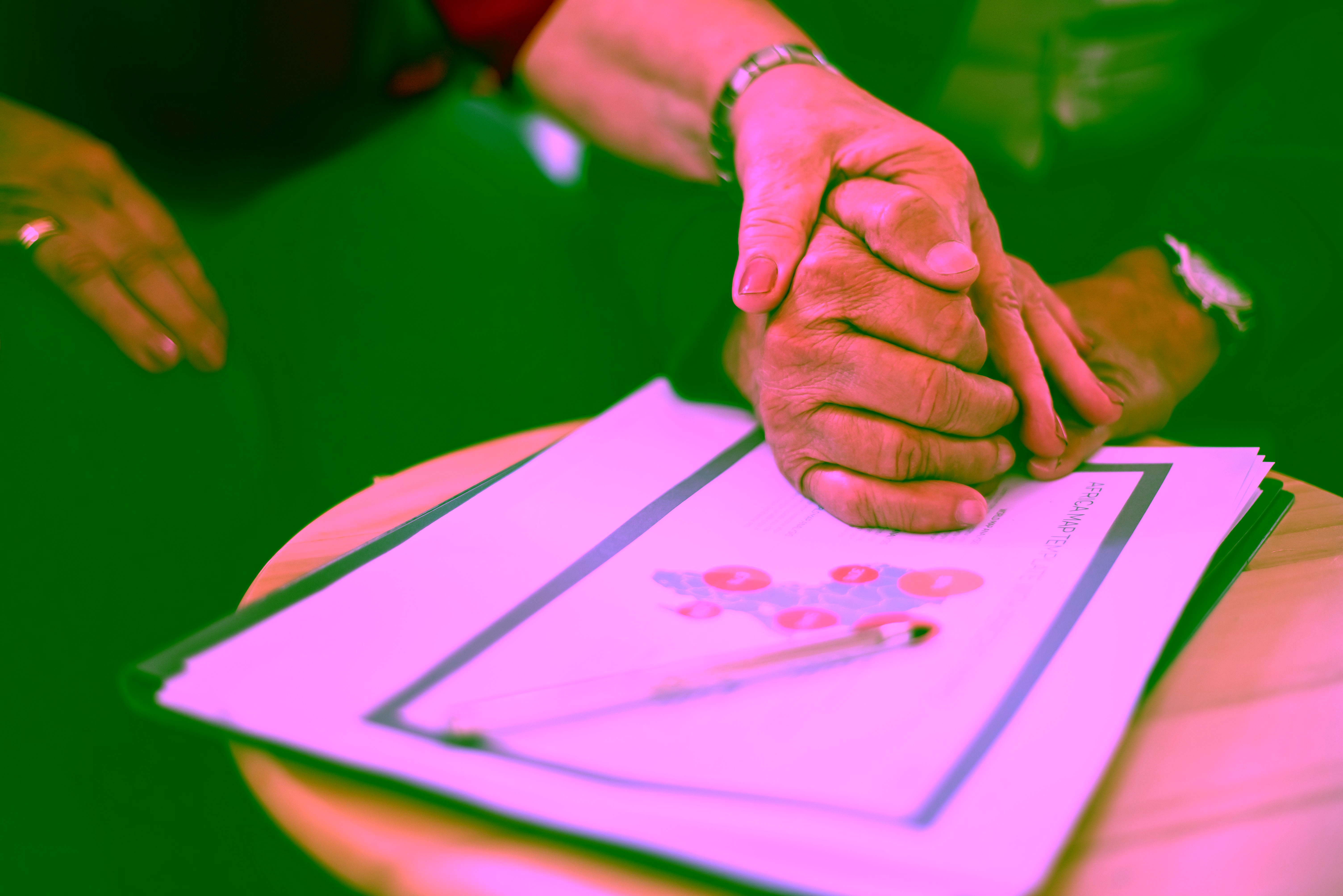 Two adults holding hands over a folder of financial documents.